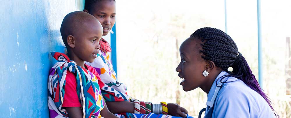 Woman kneeling and talking with two children