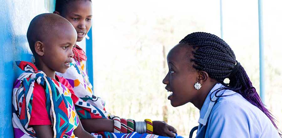 Woman kneeling and talking with two children