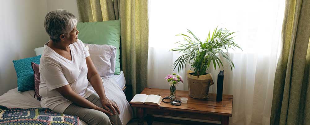 Woman sitting on a bed looking toward window