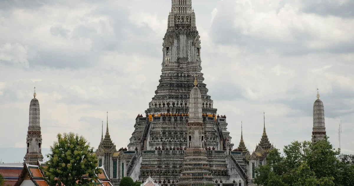 The ornate central prang of Wat Arun temple rising over Bangkok's Chao Phraya riverside.  (source: https://images.unsplash.com/photo-1755251042986-91270ffd76f5)