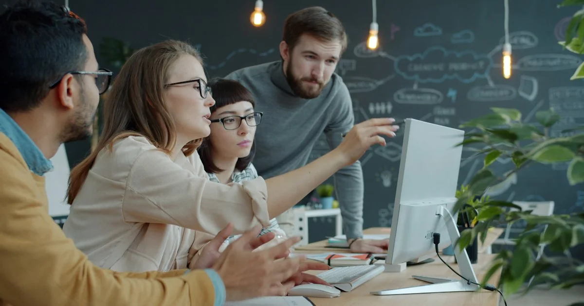 A team collaborating around a laptop in a modern office while comparing travel platforms.  (source: https://images.unsplash.com/photo-1758873268745-dd2cf0d677b5)