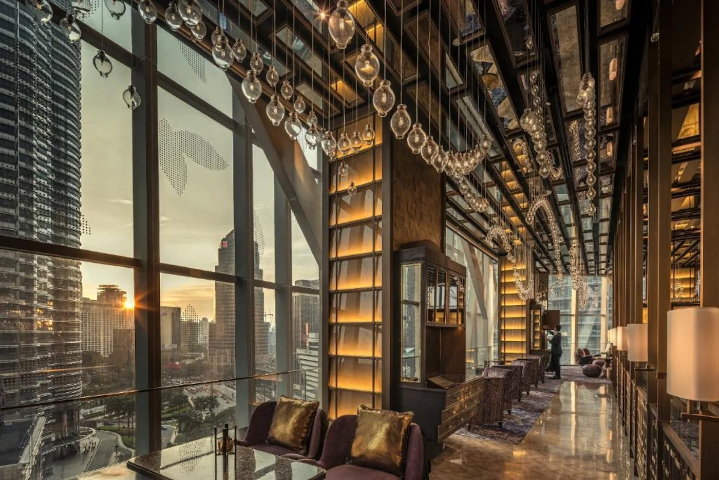A lounge with full-height glass looking onto the Petronas Towers at sunset.