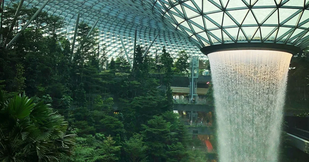 The Rain Vortex waterfall inside Jewel Changi Airport's glass-domed indoor forest.  (source: https://images.unsplash.com/photo-1568734840819-8c5f8ae2bf92)