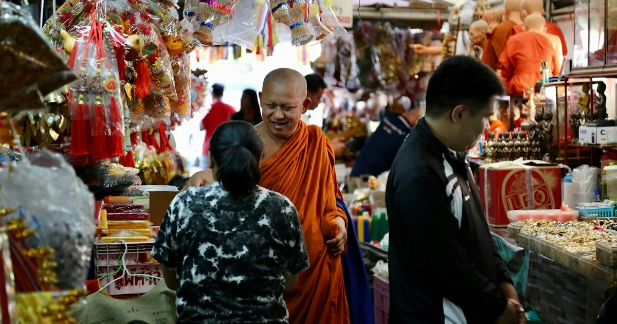 A Buddhist monk walking through a busy covered fresh market in Bangkok.  (source: https://images.unsplash.com/photo-1599725383285-a371987c2039)