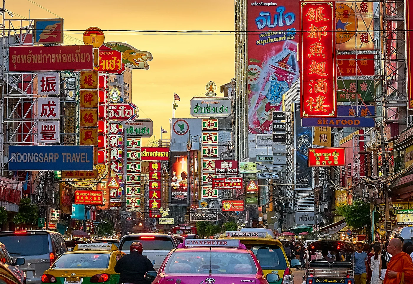 Bangkok Chinatown street crammed with colorful Chinese and Thai shop signs and taxis at sunset