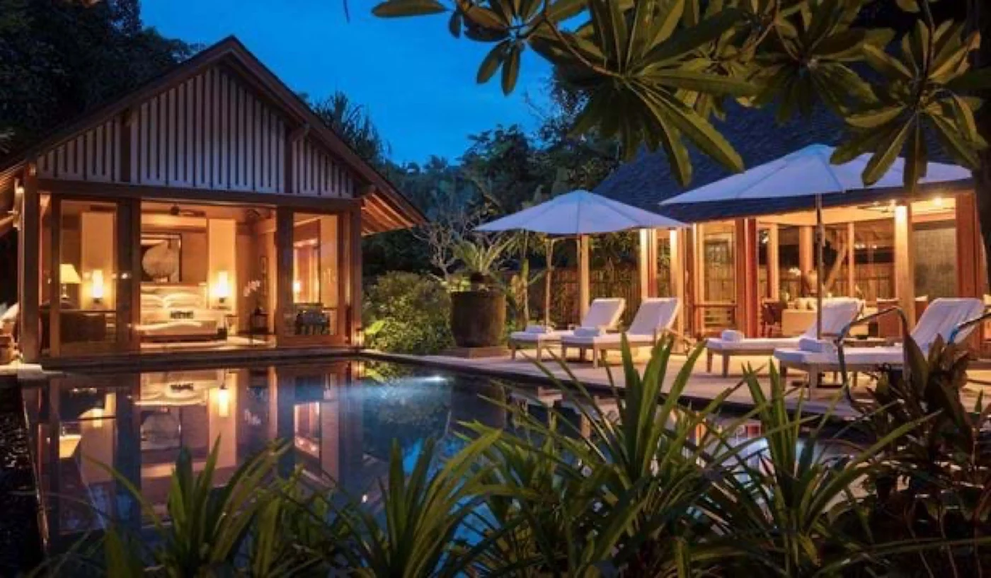 A rainforest villa and pool lit at dusk, set inside the Langkawi jungle canopy.