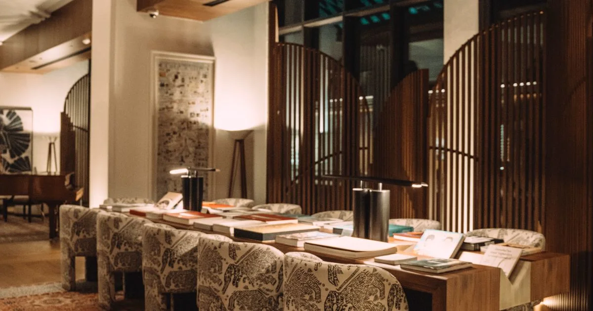 A warmly lit, upscale hotel lobby with plush armchairs and a marble floor.  (source: https://images.pexels.com/photos/31080809/pexels-photo-31080809.jpeg)