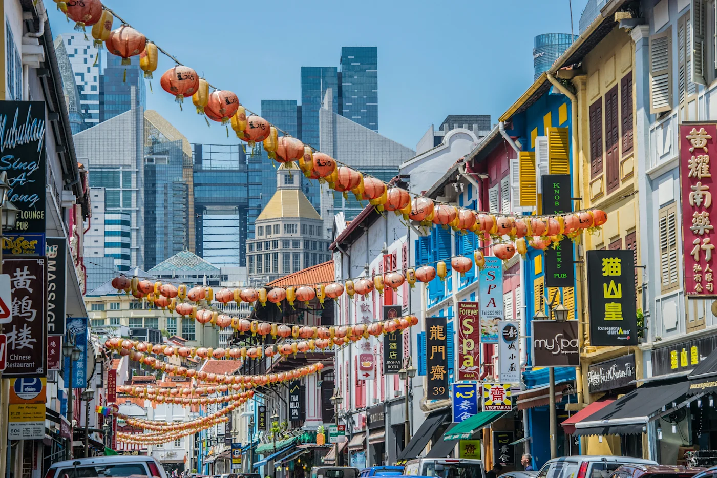 Chinatown street strung with red lanterns above colourful shophouses with skyscrapers behind