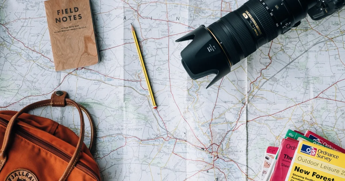 A flat-lay of a map, camera, and notebook representing early travel-business planning.  (source: https://images.unsplash.com/photo-1488646953014-85cb44e25828)