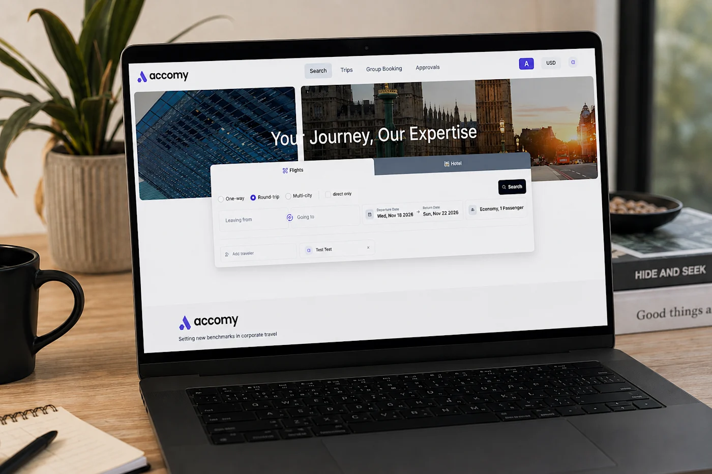 Laptop displaying the Accomy corporate travel booking site with a flight search form on a desk