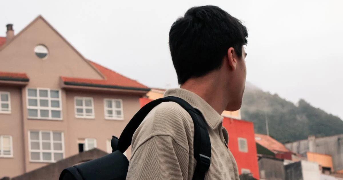A traveller with a backpack pauses on a city street between meetings, taking in the skyline.