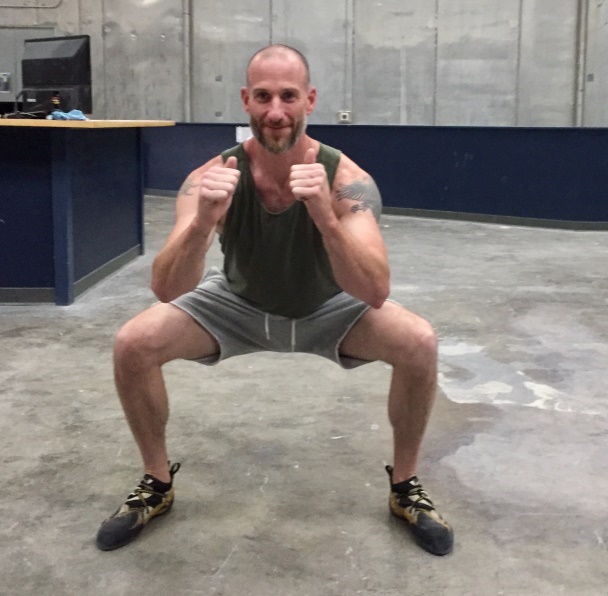 Male Climber Doing Deep Squat Stretches