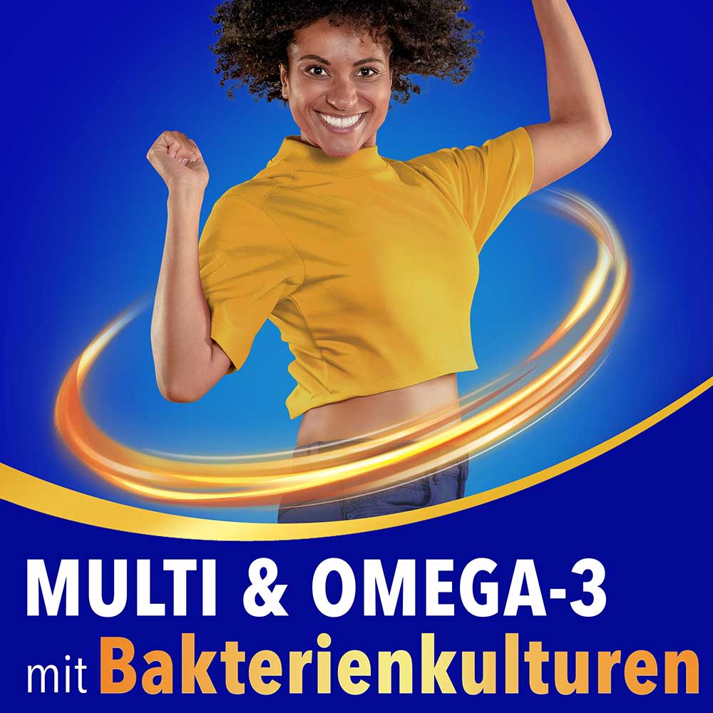 Lächelnde Frau im gelben Shirt springt energiegeladen vor blauem Hintergrund mit dem Text „Multi & Omega-3 mit bakterienkulturen“