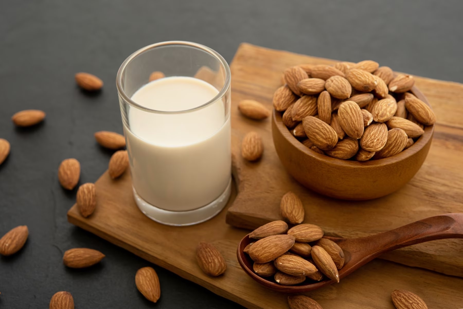 Image of glass of almond milk with bowl and spoon of whole almonds