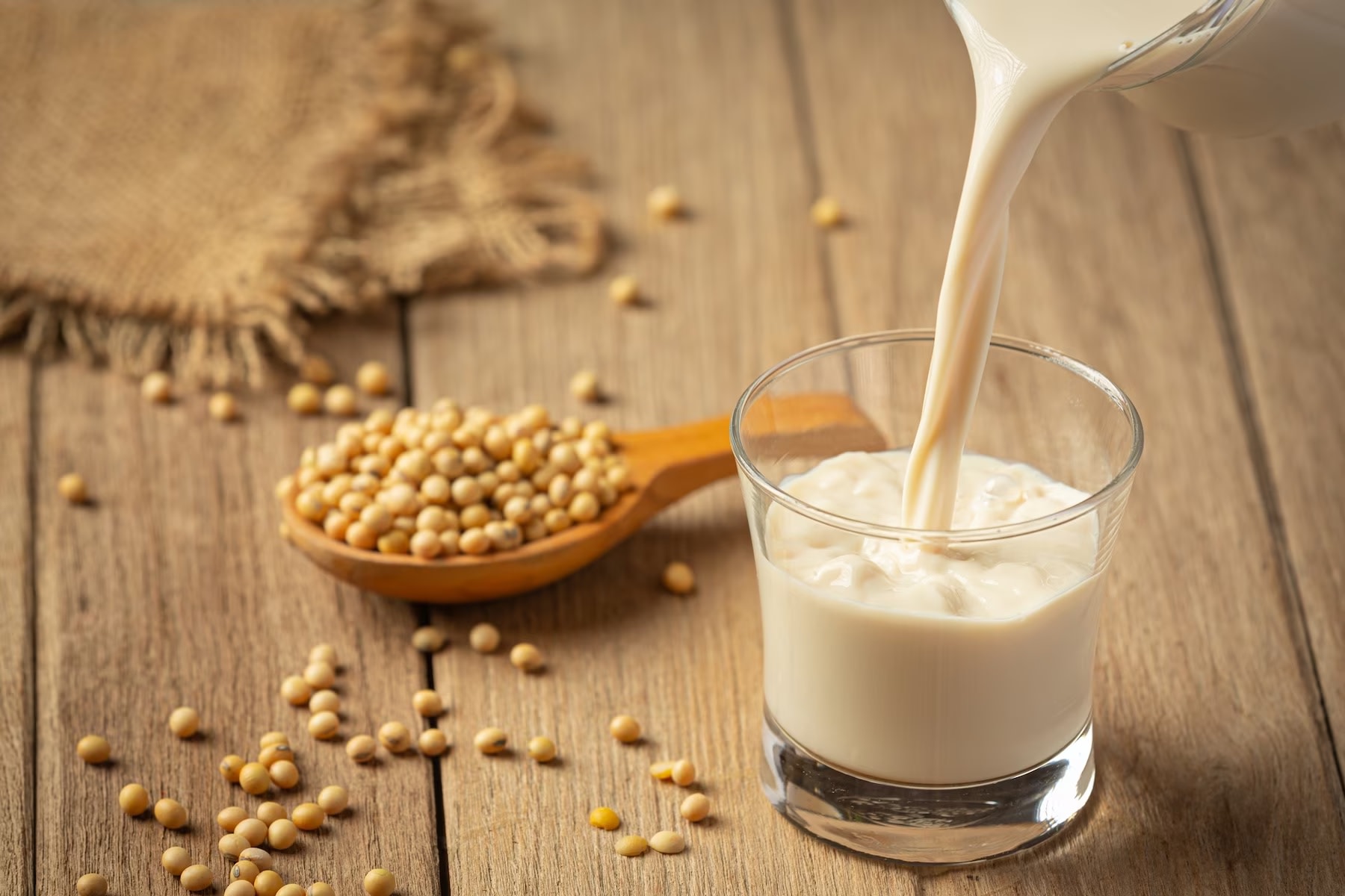 Image of glass of fresh poured soy milk and spoonful of soy beans
