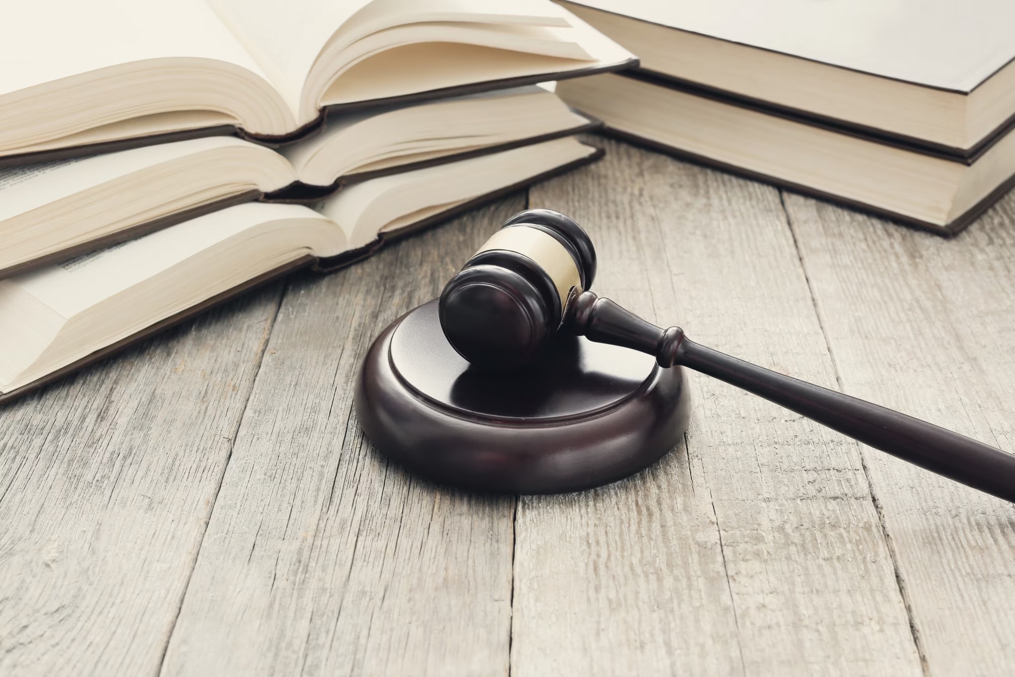 Image of courtroom gavel resting on wooden table with legal books