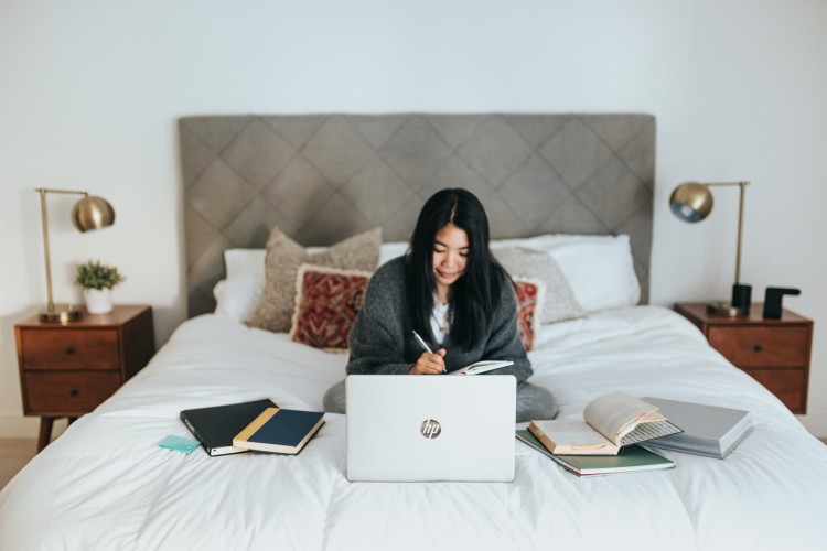 Image of woman working from home, on bed