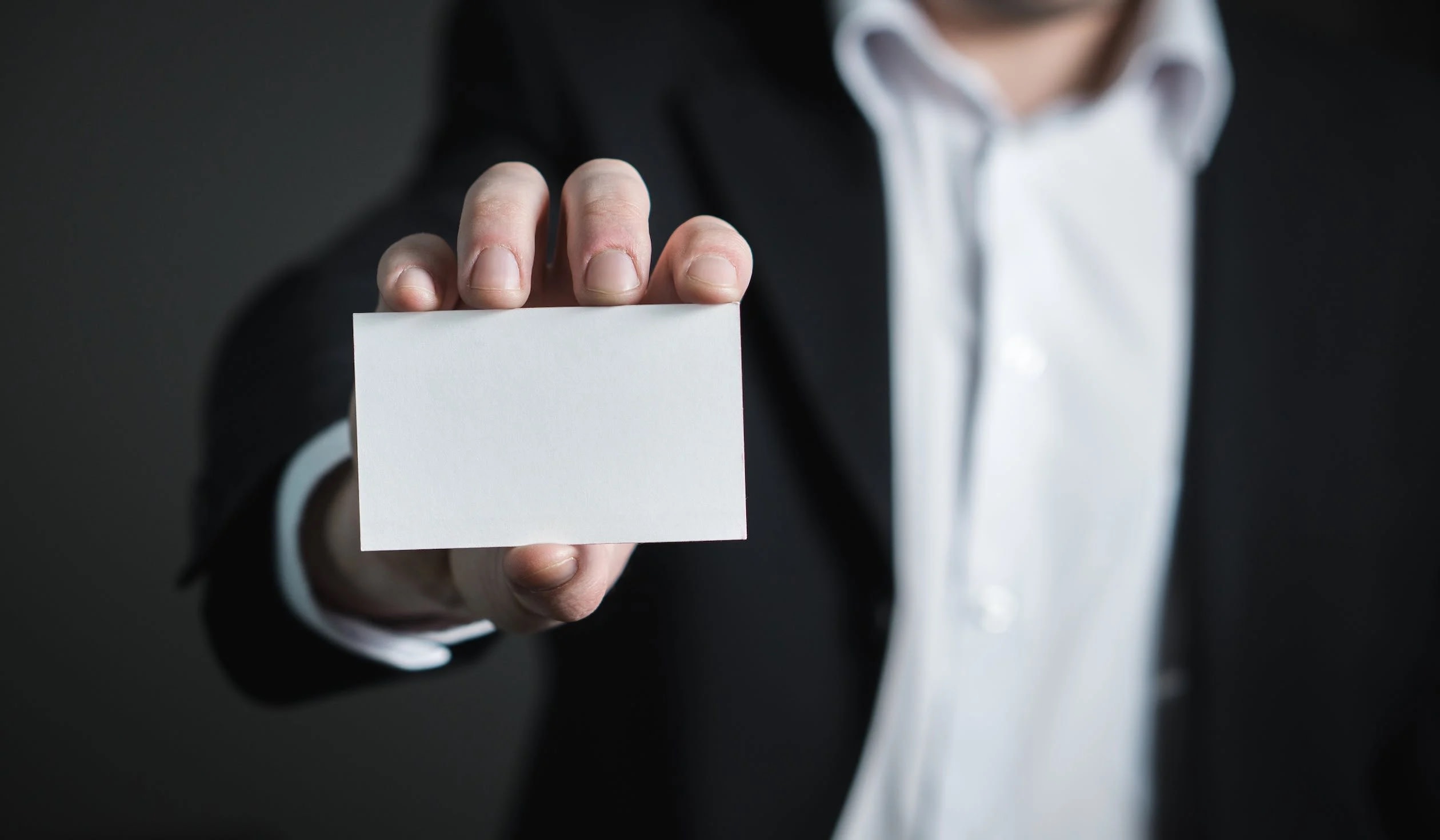 Image of blank paper card held by Caucasian man in business suit