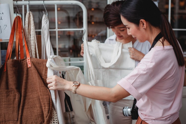 Image of trendy Asian women choosing cotton garments in a boutique