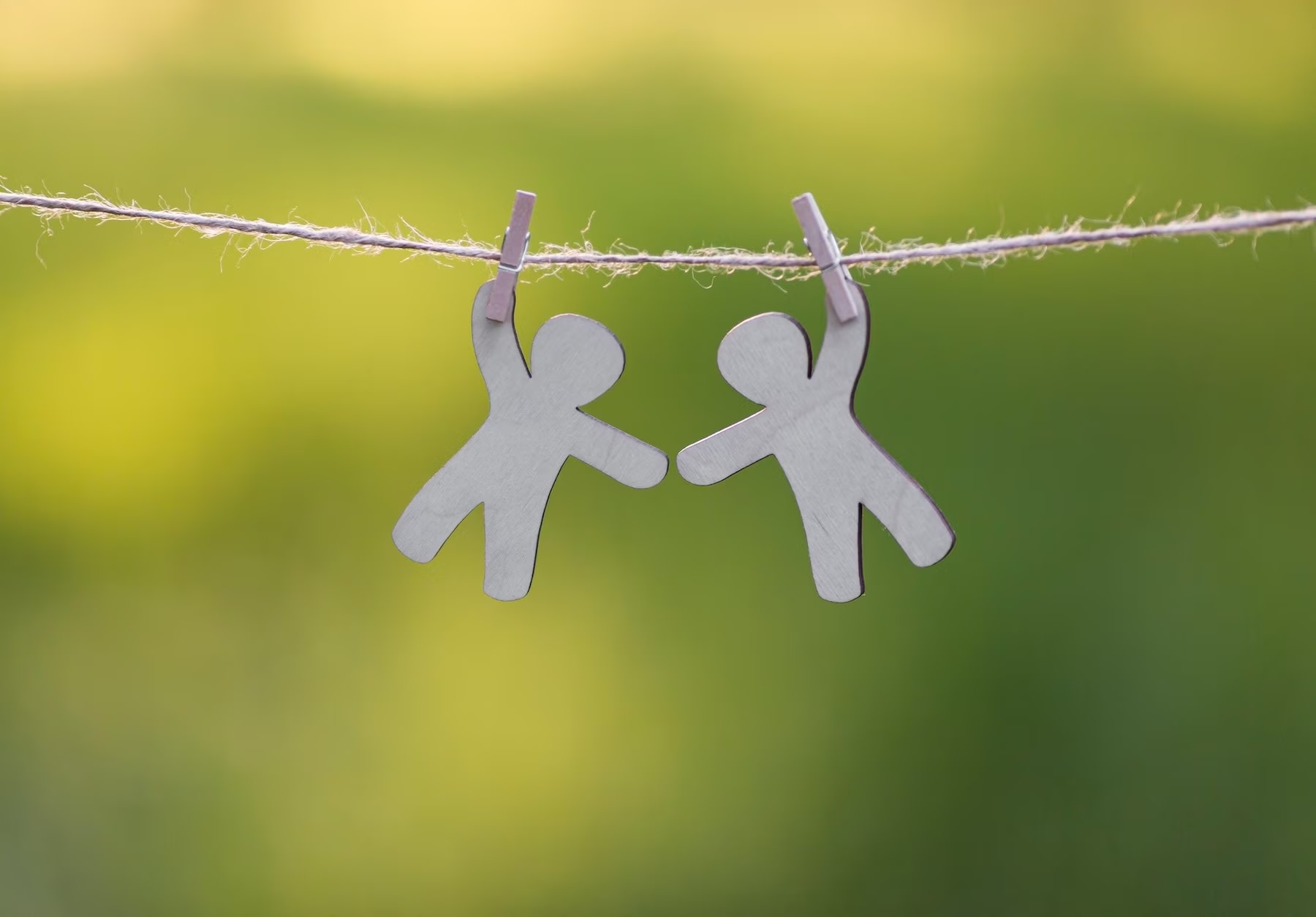Image of two paper cutouts of human figures hanging on a string