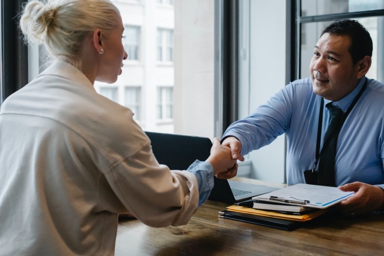 Image of man and woman shaking hands over table, example of interview