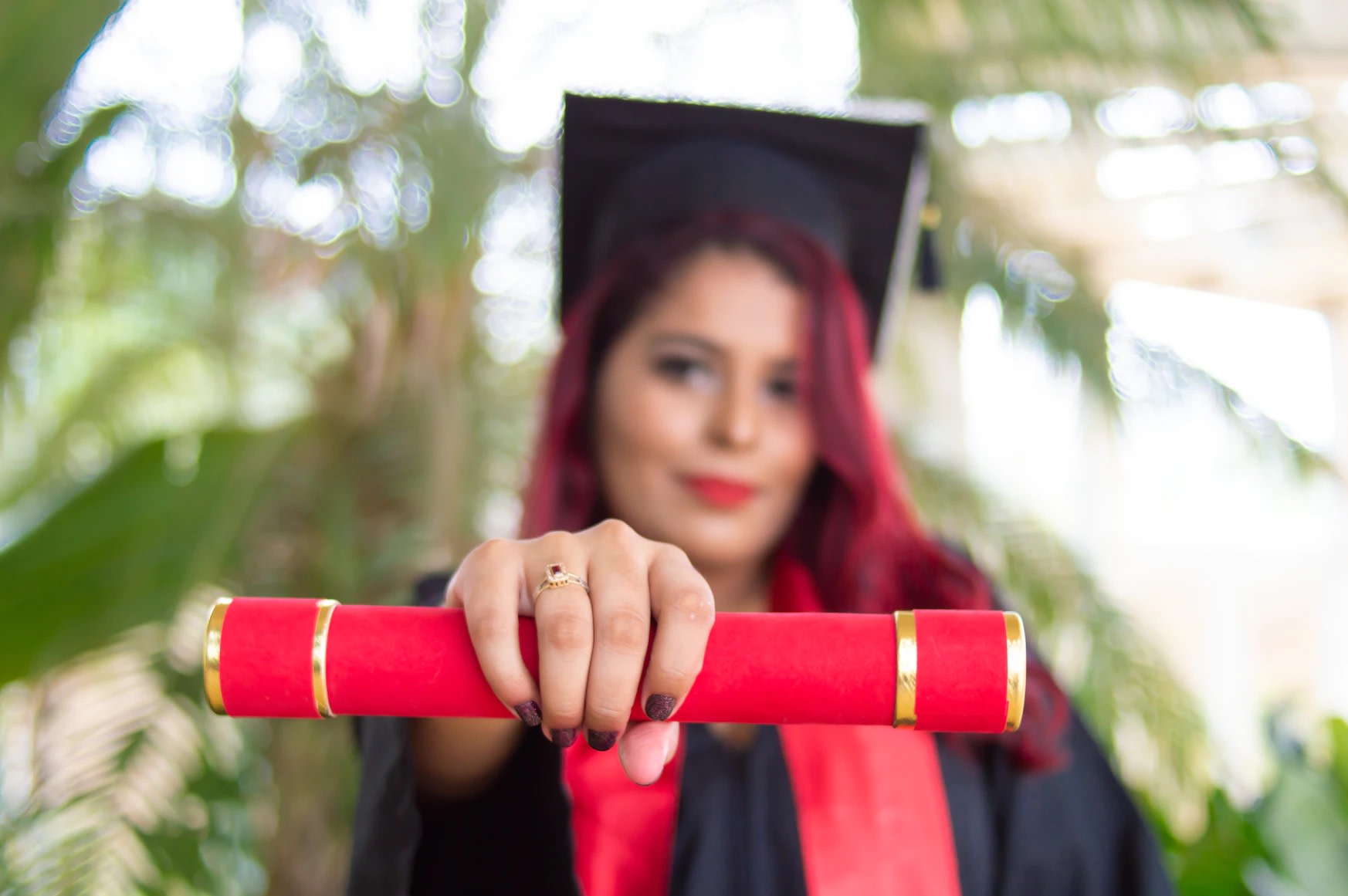 Image of red-haired woman in mortar board holding red graduation scroll