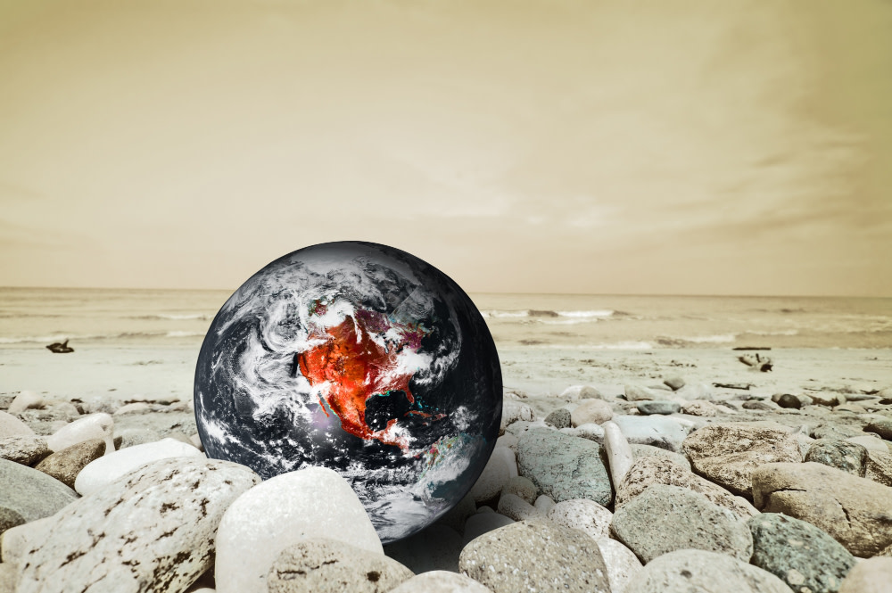 Image of Earth globe nestled in rocks on desolate plain