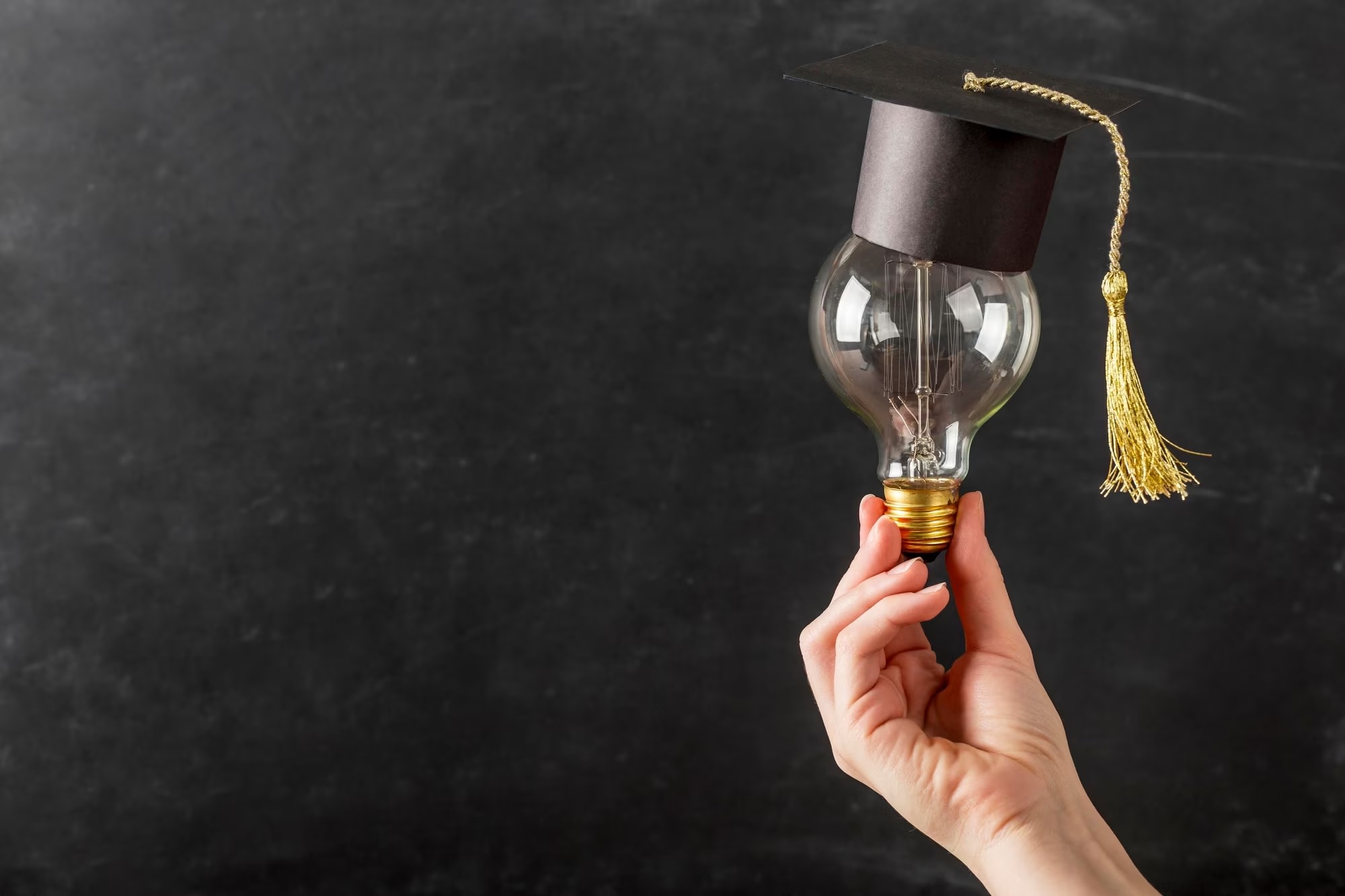 Image of hand holding light bulb with academic mortar board on top