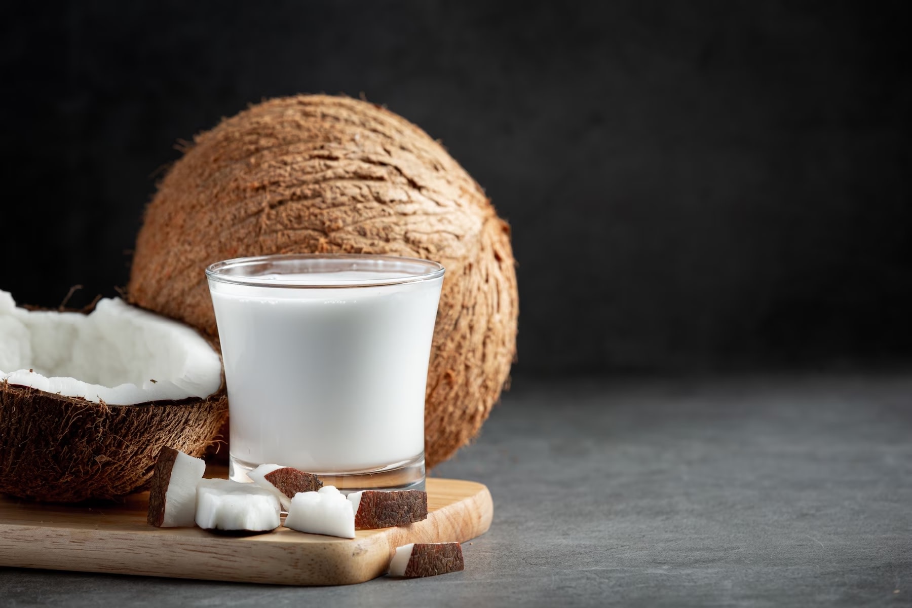 Image of glass of coconut milk with whole and half fresh coconut