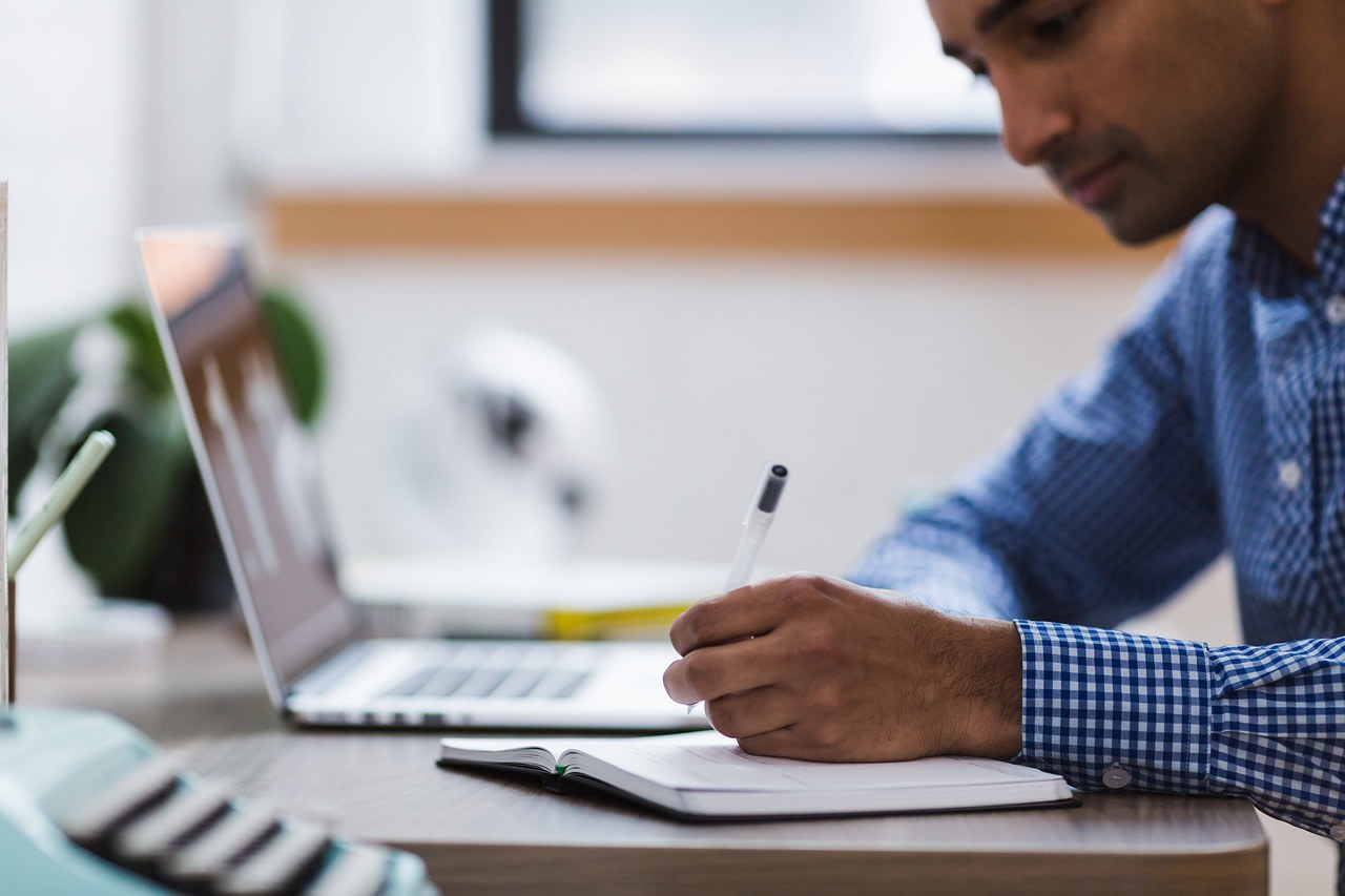 Man dressed business casual making study notes in the workplace