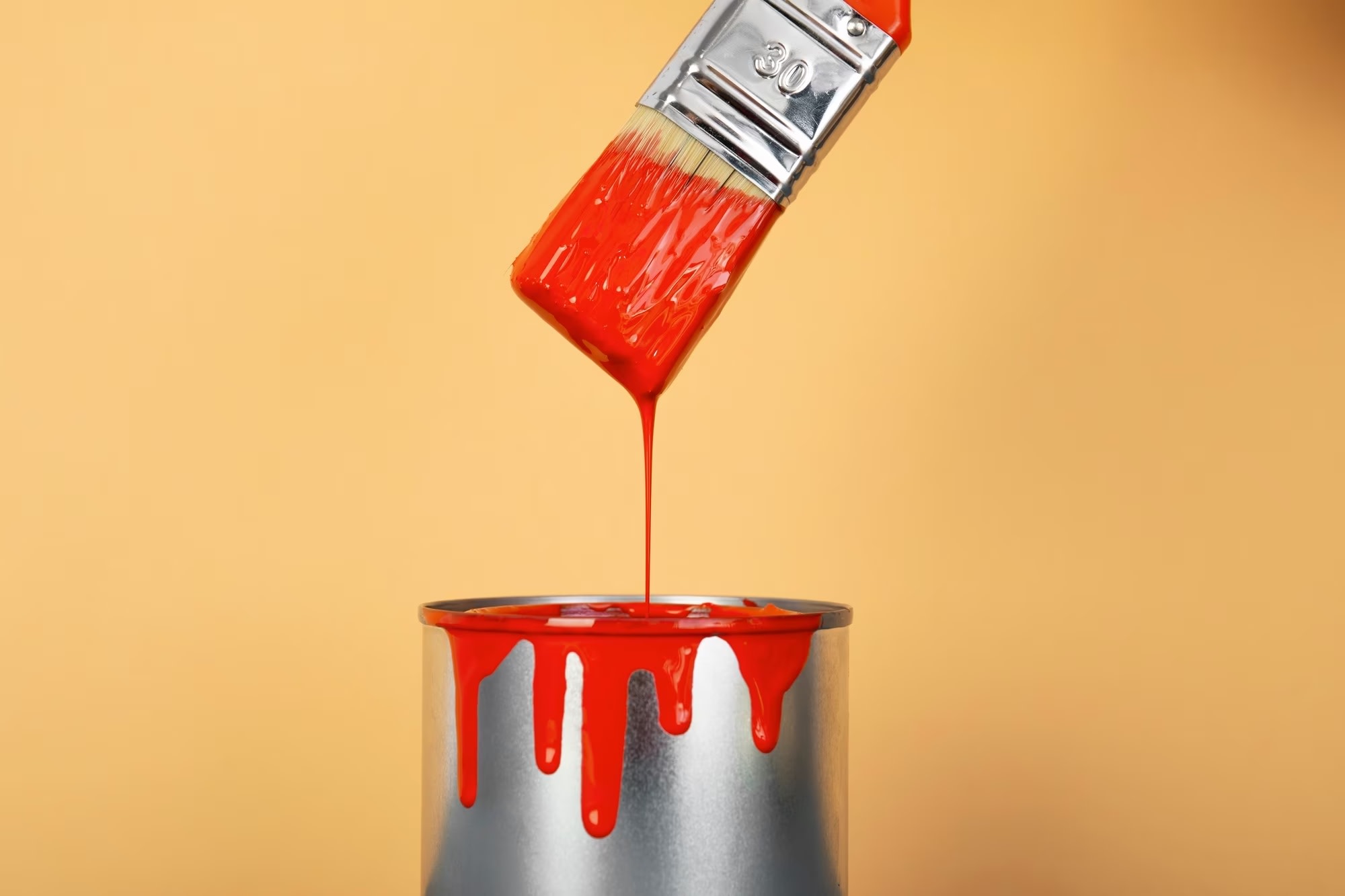 Image of paint brush dripping red paint into can