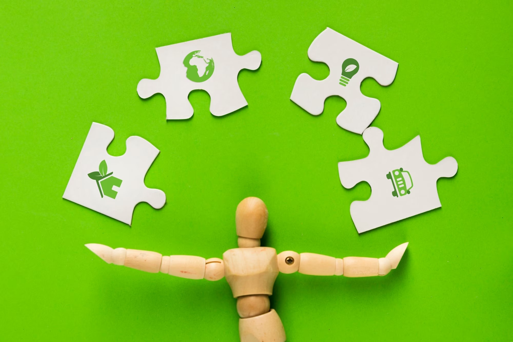 Image of white sustainability jigsaw puzzle pieces being juggled by wooden figure