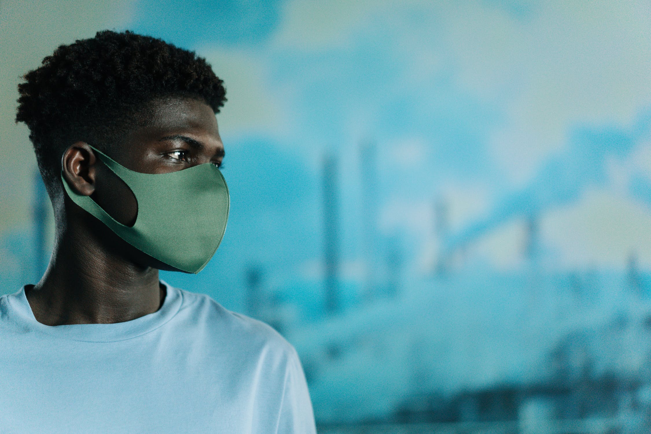 Image of young man in face mask with polluting industry in background.