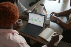 Three people having a meeting around a laptop