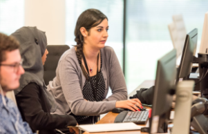 two women typing on computer at desk