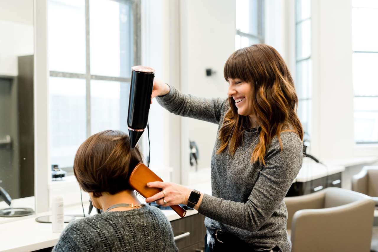 Woman drying another woman's hair at hairdressers