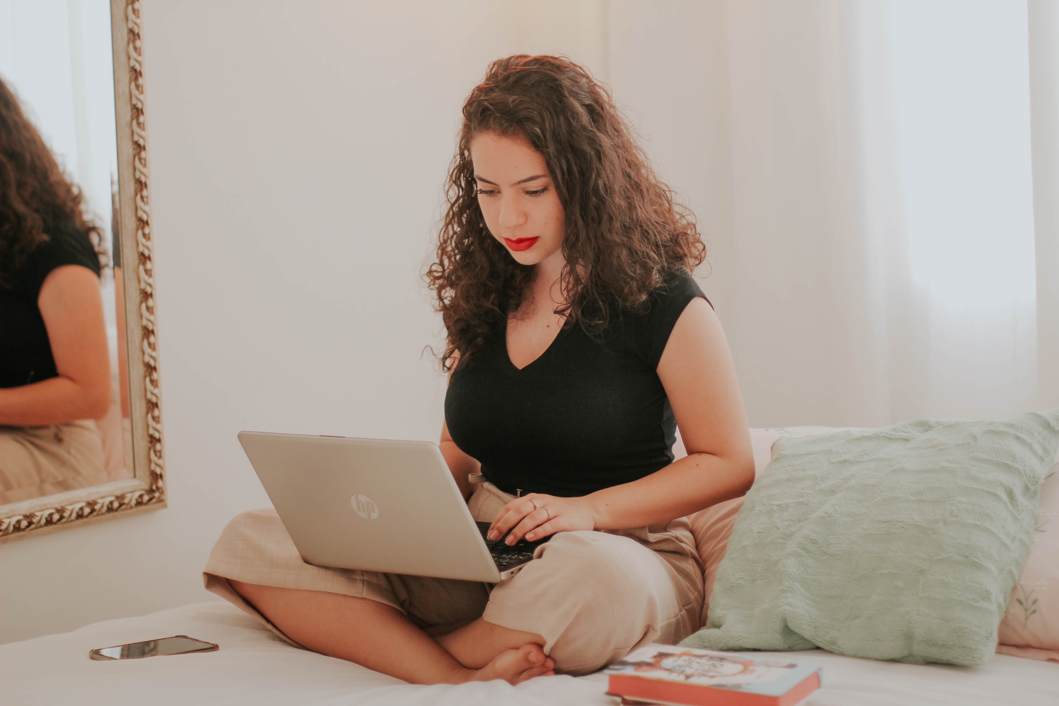 Women working at laptop on bed