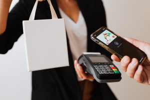 Woman handing over shopping whilst someone makes payment via credit card terminal