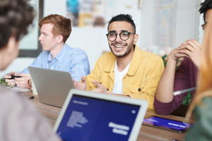 A man chatting with colleagues around his laptop