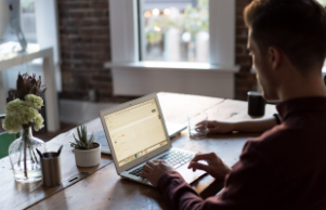 man typing at desk on laptop