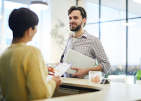 young-programmer-talking-to-hotel-receptionist-2023-11-27-05-09-09-utc