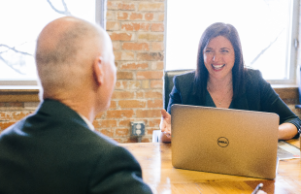 man facing woman whilst she types on laptop