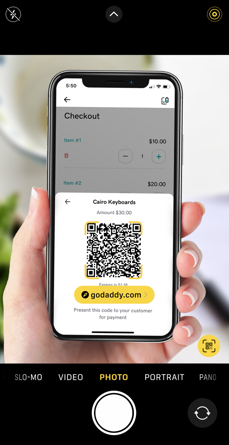 Image of a phone that is currently scanning the QR code, with a link to godaddy.com.