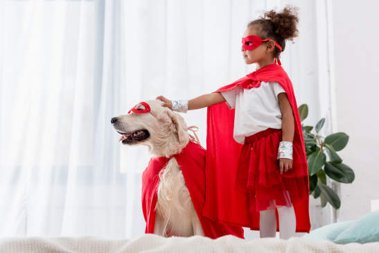 Canva - Side view of cute little african american kid and dog standing on the bed