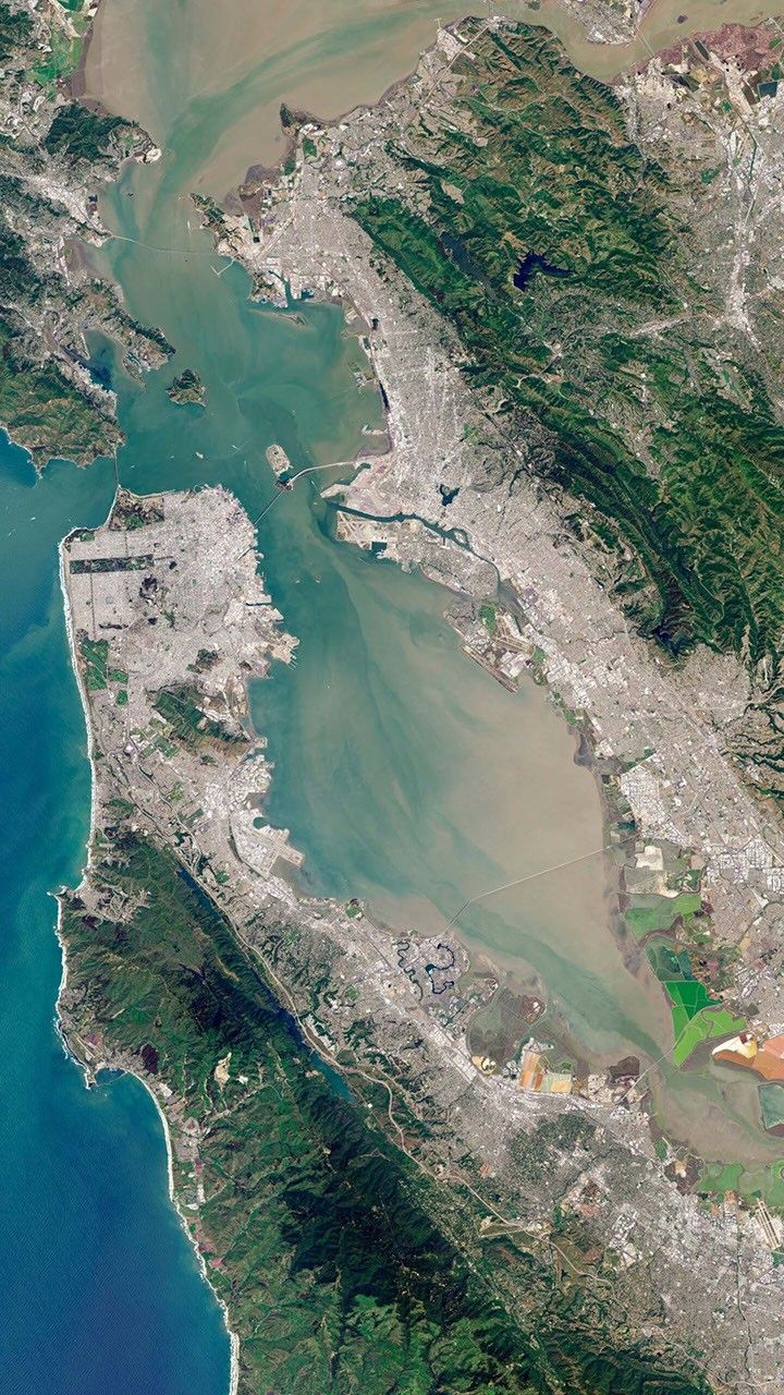 Snímek Landsatu vykresluje estuár, městské okraje a solné rybníky, díky nimž lze záliv číst jako regionální systém. Kredit: NASA/USGS Landsat via Wikimedia Commons, public domain