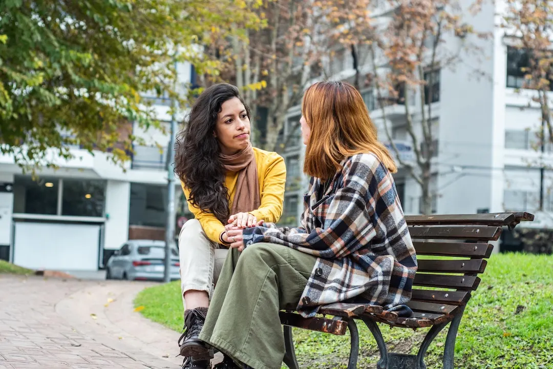 Two friends have a conversation in a park.