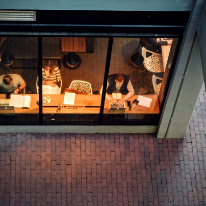 three-people-working-on-laptops-through-window-in-coffee-shop