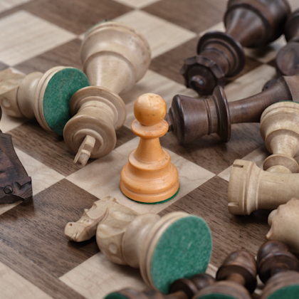 Wooden chess pieces spread on chess board