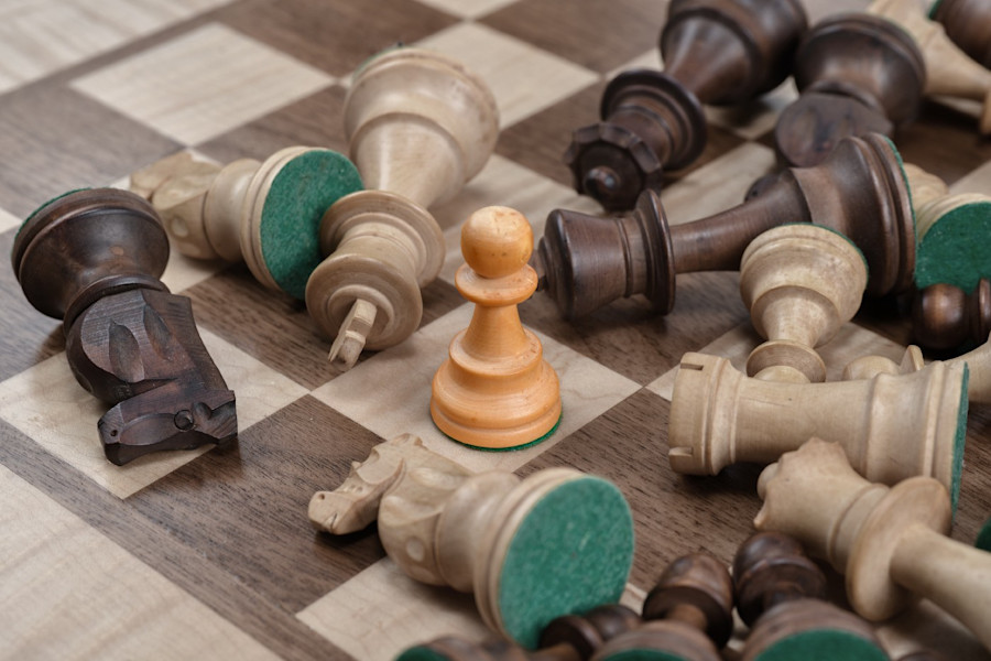 Wooden chess pieces spread on chess board