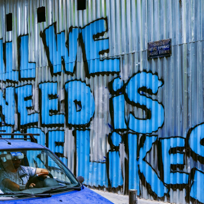 Blue graffiti on metal wall that reads 'All We Need is Likes'